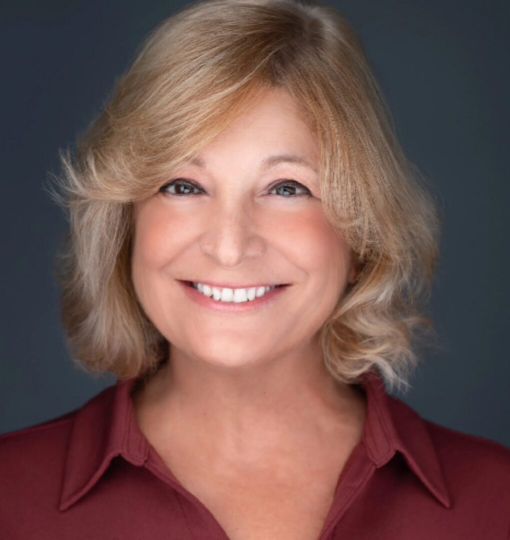 Smiling woman with blonde hair, maroon shirt