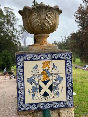 Stone urn atop a pillar with a heraldic crest in a park.