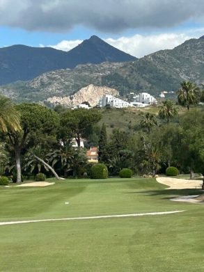 Golf course with mountains and quarry in the background.